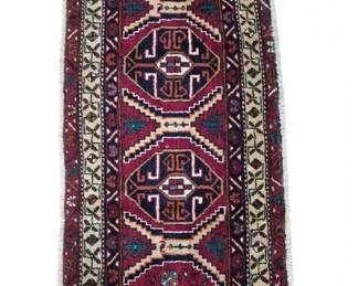 2799 - Handwoven Persian Style Wool Runner Rug 49x24 (Description): Handwoven Persian style wool runner rug  featuring a rich red field with three central  medallions in traditional geometric design.  The medallions display intricate hook motifs  in navy, cream, and teal. A cream-colored border with repeating floral and geometric  patterns frames the central field, while an  outer border in deep red completes the  design. The rug shows classic tribal weaving  characteristics with natural fringe ends.