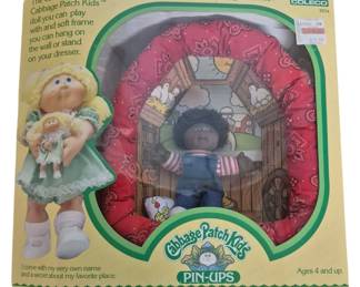 4161 - Coleco Cabbage Patch Kids Pin-Ups Doll (Description): Coleco Cabbage Patch Kids Pin-Ups collectible  doll. This vintage toy features a Cabbage  Patch Kid doll with a soft frame designed to  hang on the wall or stand on a dresser. Comes  in original packaging.
