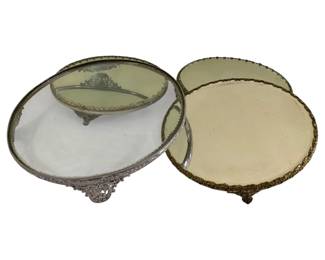 584 - 4 Plateau Centerpiece Stands (Description): One 12-inch framed glass plateau and three  10-inch mirrored plateaus. All feature  decorative metal frames with ornate detailing  and footed bases.