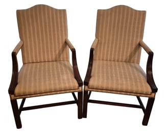 3815 - Pr Martha Washington Arm Chairs by Hickory (Description): Pair of Martha Washington arm chairs by  Hickory. These elegant chairs feature  mahogany frames with reeded arms and  stretcher bases in the classic Chippendale  style. Upholstered in a neutral striped fabric with brass nailhead trim accenting the  seat edges. The chairs have gracefully  curved camel backs and padded open arms.  Measures 40 inches high by 24 inches wide by  22 inches deep.
