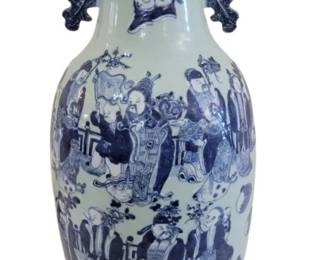434 - Chinese Blue & White Porcelain Vase w/ Stand (Description): Chinese blue and white porcelain vase with  wood stand. The vase features a classic  baluster form with a flared rim and ornate  pierced handles. The body is decorated with  detailed figural scenes depicting scholars, immortals, and attendants in traditional  settings. The vase rests on a carved wooden  display stand. Measures 24 inches tall by 13  inches wide.