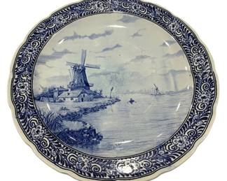 996 - Blue & White Delft Style Wall Charger 16" (Description): Blue and white Delft-style wall charger  featuring a traditional Dutch landscape scene  with a windmill, waterway, and distant  figure in a boat. The center scene is framed  by a decorative scalloped border with floral and scroll motifs. The piece appears to be  signed on the front. Measures 16 inches in  diameter.
