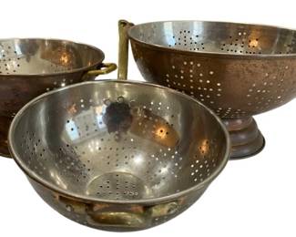 654 - Three Copper Colanders,, Largest 7"x12" (Description): These kitchen strainers feature perforated  designs for draining and brass handles with  footed bases.