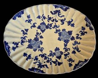 525 - Vietri Blue & White Floral Oval Platter (Description): Vietri Italian ceramic oval platter featuring  hand-painted blue and white decoration in a  floral pattern. The scalloped edge and fluted  rim frame a design of stylized chrysanthemum  blooms and scrolling foliage arranged in a circular motif. The soft cream-colored ground  provides contrast to the cobalt blue  brushwork. Measures 15" x 11.5".
