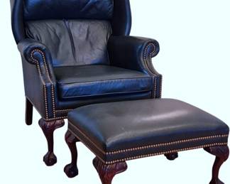 606 - Hancock & Moore Leather Chair w/ Ottoman (Description): Handsome navy blue leather wingback chair  with matching ottoman. The chair features  classic rolled arms with brass nailhead trim  detailing throughout. Both pieces rest on  carved mahogany ball and claw feet in the Chippendale style. Measures 42"x33"x36".