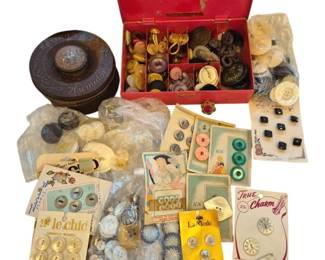 1450 - Group Vintage Buttons & Sewing Items (Description): A collection of vintage buttons and sewing  items including a red metal sewing box filled  with assorted buttons, a decorative round  tin, and numerous buttons still on their  original retail cards from brands such as Le Chic, La Mode, and True Charm. The assortment  features mother of pearl, glass, plastic,  and metal buttons in various sizes, colors,  and styles, along with loose buttons in  plastic bags. A charming assemblage for