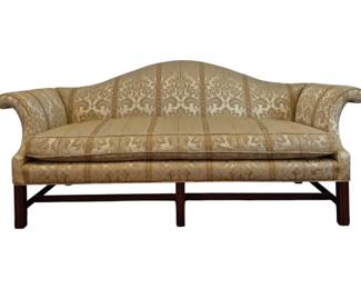 306 - Chippendale Camel Back Sofa 37"x84"x32" (Description): Chippendale style sofa featuring scrolled  arms. Upholstered in gold damask fabric with  a striped pattern. The sofa rests on a dark  wood Chippendale stretcher base with straight  legs. Measures 37" high by 84" wide by 32" deep