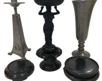 992 - Assorted Pewter, Metal & Black Glass Decor (Description): Assorted decorative items including a pewter  candlestick with pierced triangular base, a  neoclassical figural compote featuring a  draped female figure holding a swirled bowl  aloft, a pewter trumpet vase on turned base, a black glass column-form candleholder, and  several black lacquered wooden display bases  of varying sizes.