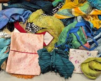 2850 - Lot of Assorted Colorful Scarves (Description): A lot of assorted scarves in a variety of  colors, patterns, and materials. The  collection includes silk and sheer fabric  scarves in shades of blue, teal, green,  yellow, pink, and multicolor combinations. Styles range from solid crinkled silk to  printed designs, embellished pieces with  sequins and beading, and fringed varieties.  An excellent assortment for accessorizing or  crafting purposes.