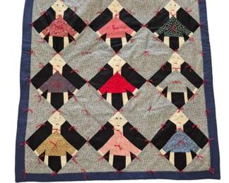 1295 - Handmade Quilt Hanger, Folk Art Girl Figures (Description): Handmade quilt featuring a charming folk art  design of girl figures arranged in a diagonal  pattern. Each figure wears a distinctive  dress in various calico and printed fabrics  including reds, blues, browns, and florals, with black arms and legs. The figures are set  against a small floral print background and  framed by a blue border. Red yarn ties secure  the quilt layers throughout. Measures 37" x  27".