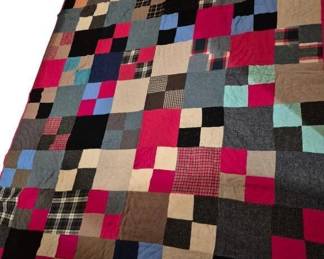 3761 - Heavy Handmade Patchwork Quilt 88x70 (Description): Featuring a classic square block pattern. The  quilt is composed of various fabric squares  in a rich array of colors including reds,  blues, blacks, browns, tans, and grays, with  both solid fabrics and plaids incorporated throughout. The piece is finished with a  magenta binding around the edges and displays  hand-stitched quilting.