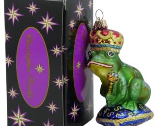2507 - Christopher Radko Frog Ornament 5.5" (Description): Christopher Radko frog ornament depicting a  crowned frog prince seated on a decorative  pillow, holding a scepter. Includes original  Christopher Radko box. Measures 5.5 inches.