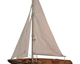 3781 - Wooden Sail Boat Model 24"x16" (Description): Wooden sail boat model featuring a classic  sloop design with canvas sails, detailed  rigging, and a finished wood deck with cabin  details. The hull is painted dark blue with a  white waterline stripe. Mounted on a wooden display stand with brass-toned support  bracket.