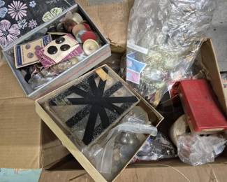 4105 - Box Lot of Vtg Buttons & Sewing Notions (Description): Box lot of vintage buttons and sewing  notions. The collection includes assorted  loose buttons in various sizes, colors, and  materials, buttons still on original display  cards, wooden thread spools, and additional sewing supplies. Items are housed in  decorative boxes including a floral-patterned  container and various smaller boxes.