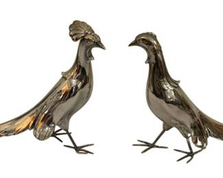 292 - Alfred Flauder Buffet Birds Pheasants 7.5x12 (Description): A pair of decorative buffet birds by Alfred  Flauder, featuring elegant pheasant figures  in a polished silver-tone metal finish. The  birds are beautifully detailed with graceful  long tail feathers, textured plumage on the bodies, and delicate wire feet. One pheasant  displays a decorative crest on its head while  the other has a sleeker profile, creating a  complementary pair ideal for table  centerpiece or sideboard display. Each