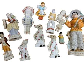 4187 - Group Lot of Porcelain Figurines (Description): Group lot of porcelain figurines featuring an  assortment of hand-painted pieces. The  collection includes various figures in  traditional and folk costumes, decorative  dogs with red spot details, and children in period dress. Several pieces appear to be  vintage bisque or glazed porcelain with  polychrome painted decoration. The lot  includes both complete figures and some with  minor losses.
