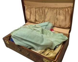 4166 - Vtg Suitcase w/ Vtg Dresses (Description): A vintage suitcase containing a collection of  vintage dresses. The suitcase features a  classic design with brass hardware and a  satin-lined interior. The dresses inside  showcase various styles and fabrics from the era.