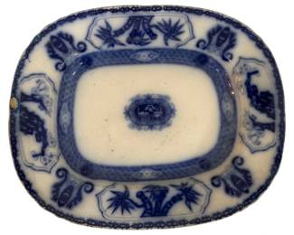 297 - Thibet Flow Blue Porcelain Platter 15"x13" (Description): Tibet pattern blue and white porcelain  platter measuring 15 inches by 13 inches.  This flow blue style serving piece features a  central medallion with a scenic vignette,  surrounded by an inner border of geometric diaper pattern. The wide rim is decorated  with alternating cartouches containing bamboo  plants and botanical motifs, connected by  scrollwork bands. The platter has a  rectangular form with softly rounded corners,