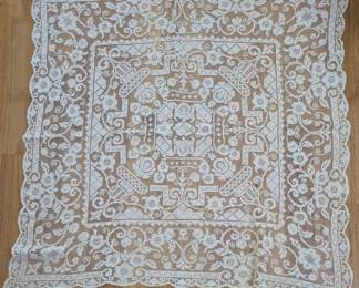 1298 - Vtg Filet Lace Tablecloth w/ Crown Motif (Description): Vintage filet lace tablecloth featuring an  intricate design with a central crown motif  surrounded by scrolling floral patterns and  geometric borders. The piece displays fine  handcrafted lacework in an ecru or ivory tone with a scalloped edge. Measures 45" x 44".