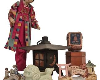 3947 - Group Lot of Oriental Decorative Items (Description): A group lot of oriental items including a  decorative Korean-style doll figure wearing  traditional colorful hanbok attire, a metal  pagoda-style lantern with moon and star  cutouts, a celadon glazed foo dog figurine, ceramic bridge and pagoda planters or  decorative pieces, small porcelain geisha  figurines, and boxed jasmine tea in  traditional packaging. An eclectic assortment  of Asian-inspired decorative objects.