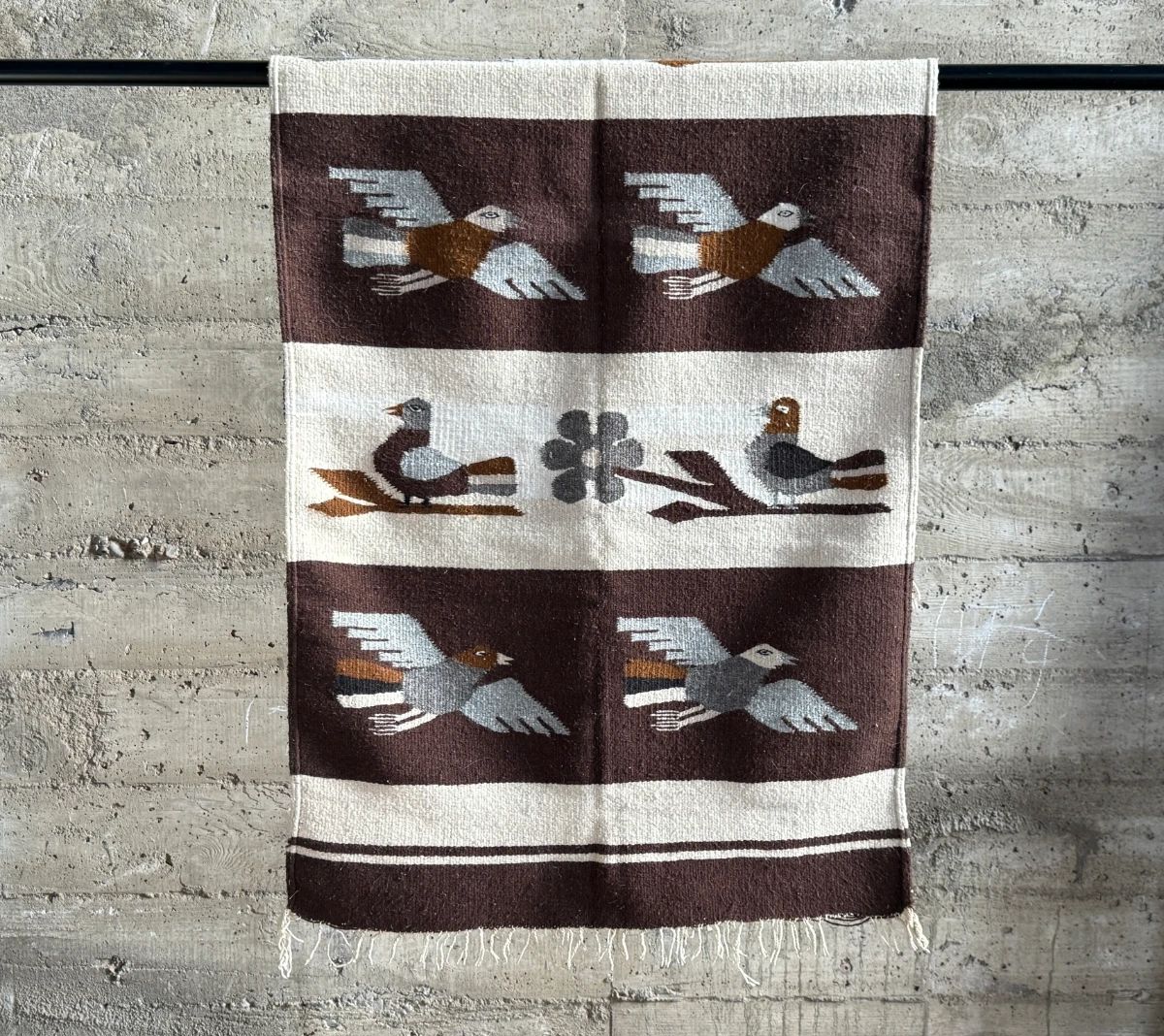 This lot features a Zapotec Indian handwoven wool rug featuring a stylized bird pattern. It is crafted in Oaxaca, Mexico, using traditional weaving techniques. This rug measures, 64” H x 29” W.