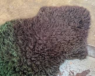 This lot features a genuine sheepskin rug with black and green tint that measures, 38” H x 24” W.