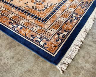 This lot features a Karastan Cathay Medallion area rug featuring a beige field and blue borders that measures, 120” H x 104” W.