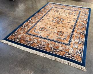 This lot features a Karastan Cathay Medallion area rug featuring a beige field and blue borders that measures, 120” H x 104” W.