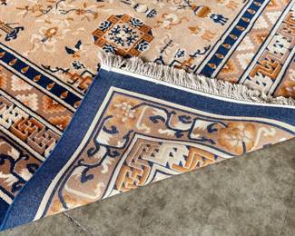 This lot features a Karastan Cathay Medallion area rug featuring a beige field and blue borders that measures, 120” H x 104” W.