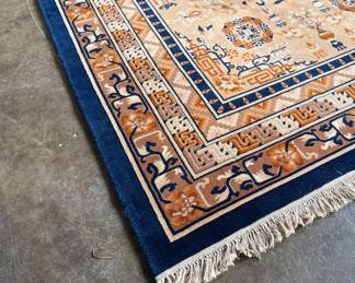 This lot features a Karastan Cathay Medallion area rug featuring a beige field and blue borders that measures, 120” H x 104” W.