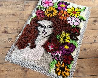 This lot features a latch hook tapestry created in the “rya style, ” a shaggy textile technique that became a home decor staple in the 1960s and ’70s. This piece measures, 36” H x 24” W.