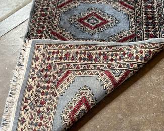 This lot features a small, hand-knotted Persian rug featuring a traditional Kazak geometric pattern with red diamond motifs on a light blue field that measures, 36” H x 24” W.