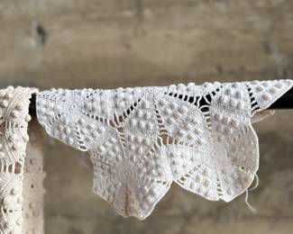 This lot features a vintage hand-crocheted lace bedspread with an intricate circular motif design and cream color. This piece is in excellent condition and comes with an additional piece for the pattern.