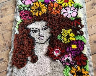 This lot features a latch hook tapestry created in the “rya style, ” a shaggy textile technique that became a home decor staple in the 1960s and ’70s. This piece measures, 36” H x 24” W.