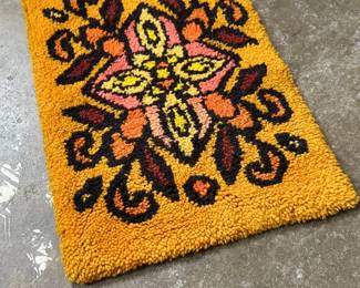 This lot features a latch hook tapestry created in the "rya style, " a shaggy textile technique that became a home decor staple in the 1960s and ’70s. This piece measures, 28” H x 20” W.