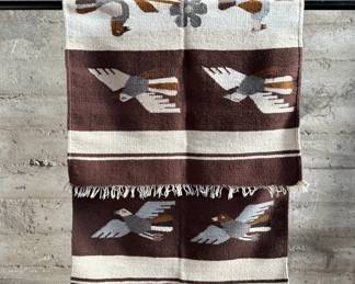 This lot features a Zapotec Indian handwoven wool rug featuring a stylized bird pattern. It is crafted in Oaxaca, Mexico, using traditional weaving techniques. This rug measures, 64” H x 29” W.