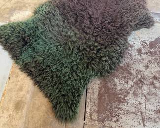 This lot features a genuine sheepskin rug with black and green tint that measures, 38” H x 24” W.