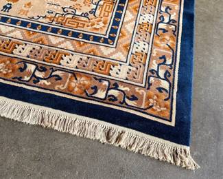 This lot features a Karastan Cathay Medallion area rug featuring a beige field and blue borders that measures, 120” H x 104” W.