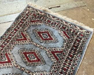 This lot features a small, hand-knotted Persian rug featuring a traditional Kazak geometric pattern with red diamond motifs on a light blue field that measures, 36” H x 24” W.