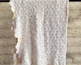 This lot features a vintage hand-crocheted lace bedspread with an intricate circular motif design and cream color. This piece is in excellent condition and comes with an additional piece for the pattern.