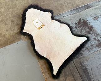 This lot features a genuine sheepskin rug with black and green tint that measures, 38” H x 24” W.