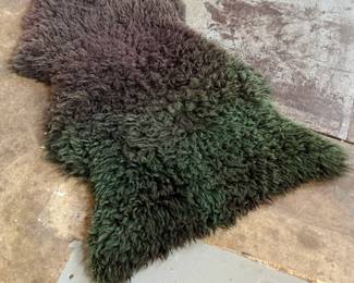 This lot features a genuine sheepskin rug with black and green tint that measures, 38” H x 24” W.