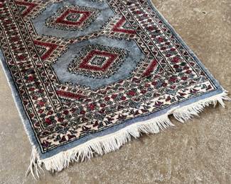 This lot features a small, hand-knotted Persian rug featuring a traditional Kazak geometric pattern with red diamond motifs on a light blue field that measures, 36” H x 24” W.