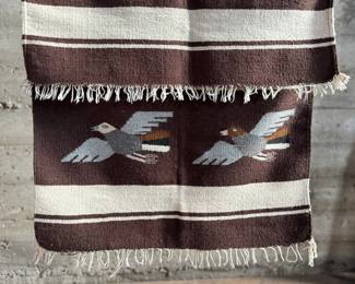 This lot features a Zapotec Indian handwoven wool rug featuring a stylized bird pattern. It is crafted in Oaxaca, Mexico, using traditional weaving techniques. This rug measures, 64” H x 29” W.