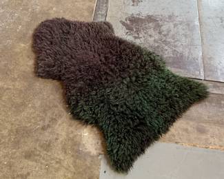 This lot features a genuine sheepskin rug with black and green tint that measures, 38” H x 24” W.