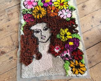This lot features a latch hook tapestry created in the “rya style, ” a shaggy textile technique that became a home decor staple in the 1960s and ’70s. This piece measures, 36” H x 24” W.