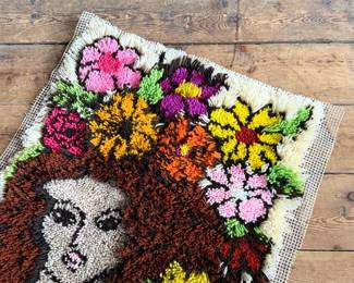 This lot features a latch hook tapestry created in the “rya style, ” a shaggy textile technique that became a home decor staple in the 1960s and ’70s. This piece measures, 36” H x 24” W.