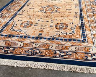 This lot features a Karastan Cathay Medallion area rug featuring a beige field and blue borders that measures, 120” H x 104” W.