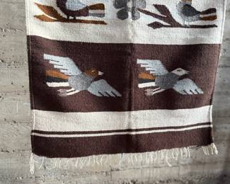 This lot features a Zapotec Indian handwoven wool rug featuring a stylized bird pattern. It is crafted in Oaxaca, Mexico, using traditional weaving techniques. This rug measures, 64” H x 29” W.