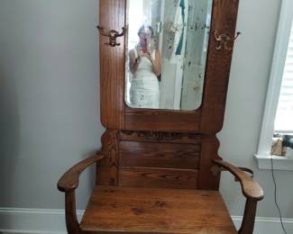 Victorian era oak hall seat featuring beveled mirror, brass hooks and a lift top storage. Purchased approximately  1914